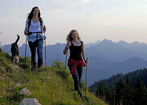 Zwei Wanderinnen mit einem Hund auf einem Bergpfad