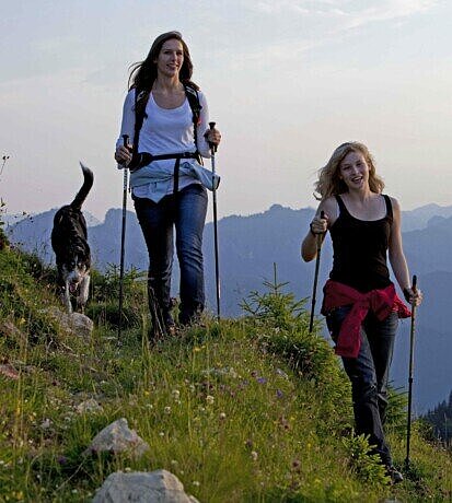 Zwei Wanderinnen mit einem Hund auf einem Bergpfad