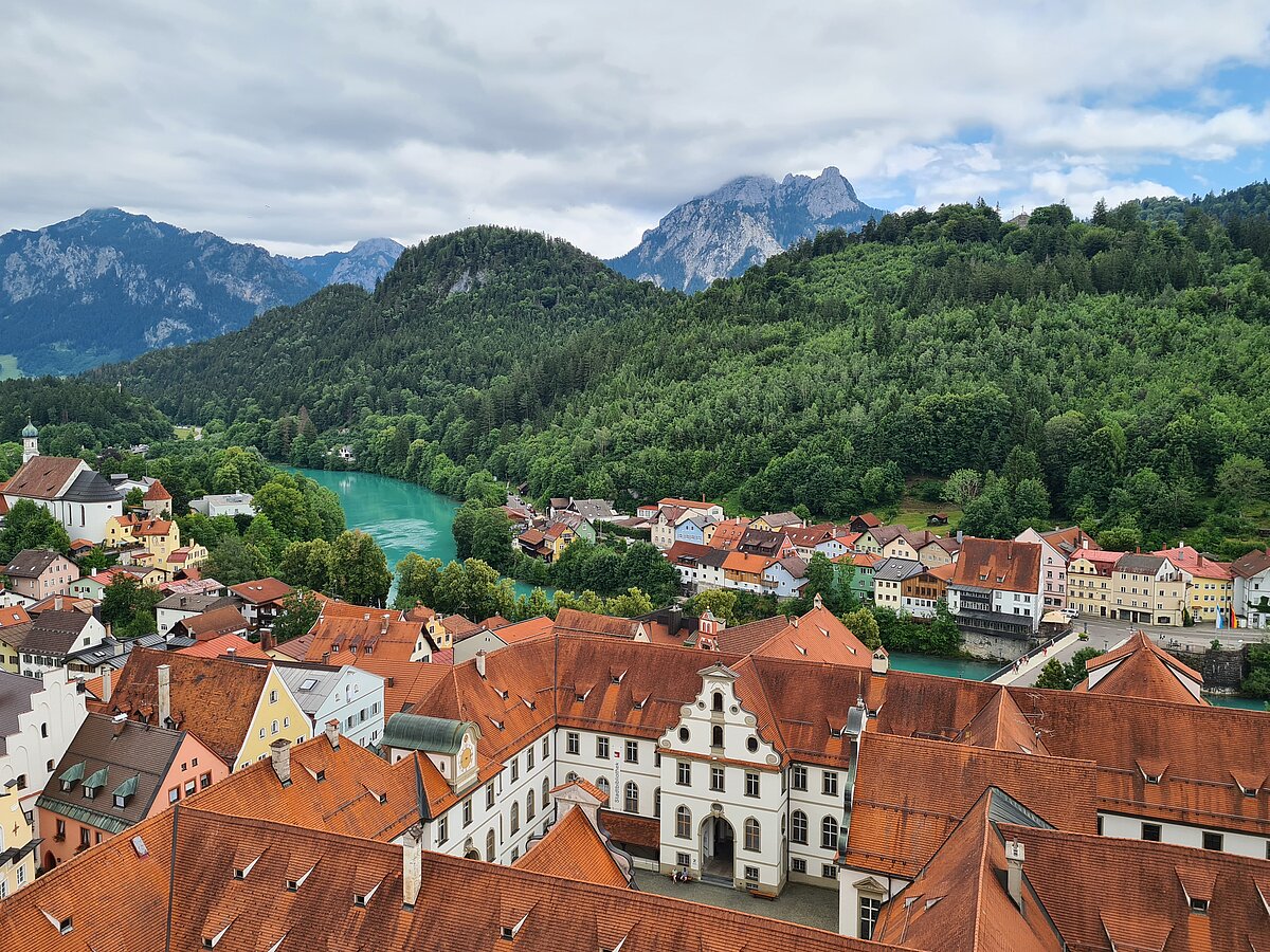 Der türkise Lech schlängelt sich unterhalb der Füssner Altstadt - im Hintergrund erstreckt sich ein imposantes Bergpanorama.