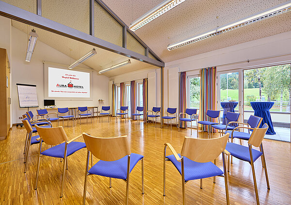 Im großen hellen Tagungsraum ist ein Stuhlkreis aufgebaut, im Hintergrund erkennt man den angeschlossenen Balkon.