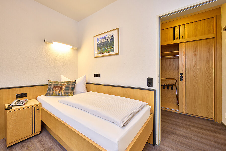 Über dem gemütlichen Bett hängt ein stimmungsvolles Landschaftsbild. Ein Durchgang führt zum großen, geräumigen Einbauschrank mit Gardarobe.