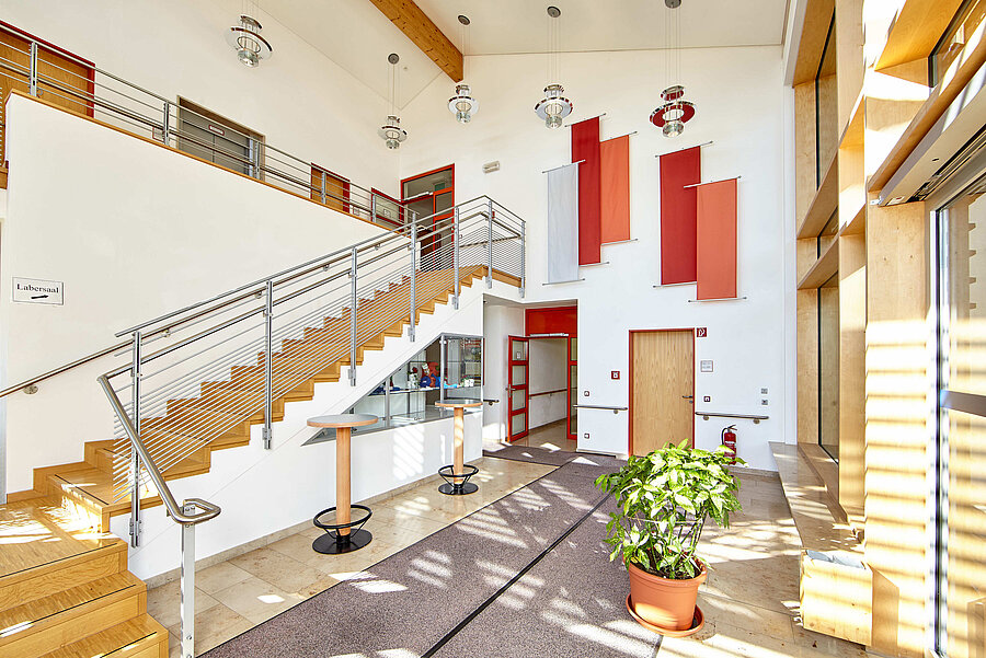 Die großzügig gestaltete Eingangshalle verbindet die beiden Etagen mit einer Holztreppe. In einem integrierten Schaukasten befinden sich blindenspezifische Hilfsmittel. 