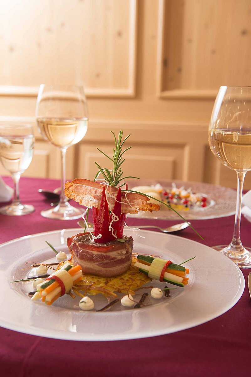 Auf einem schön gedeckten Tisch stehen Weingläser und ein hübsch angerichteter Speiseteller.