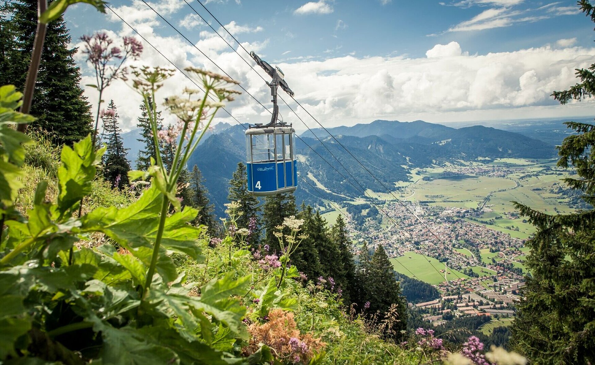 Die Gondel der Laberbahn schwebt in die Höhe und bietet einen atemberaubenden Ausblick auf das grüne Ammertal.
