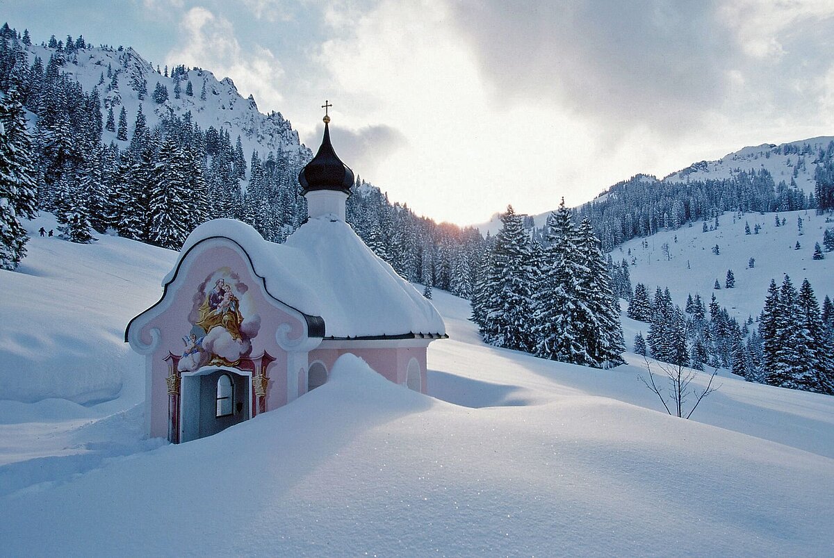 In der tiefverschneiten Winterlandschaft strahlt die bunt bemalte Josefskapelle ein friedvolles Gefühl aus.