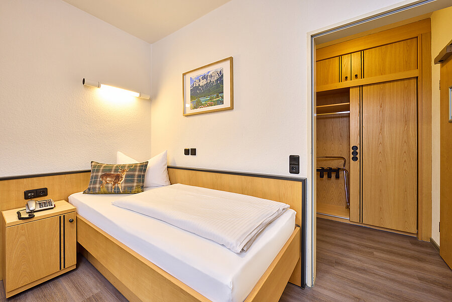 Das Einzelzimmer verfügt über helles Massivholzmobilar und eine großzügige Einbauwand mit Garderobe und Kleiderschrank.