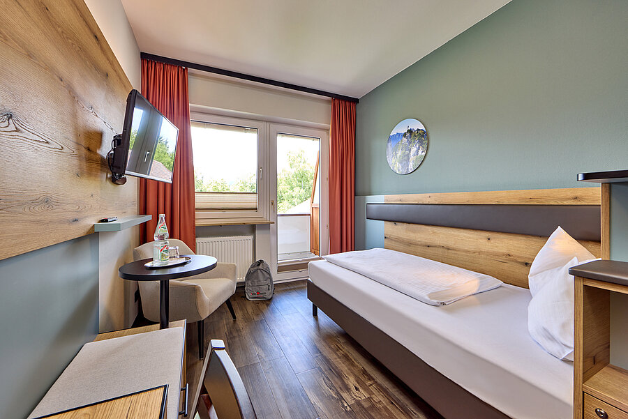 Zimmeransicht in Richtung Fenster. Links die Sitzgelegenheiten, rechts das gemütliche Bett