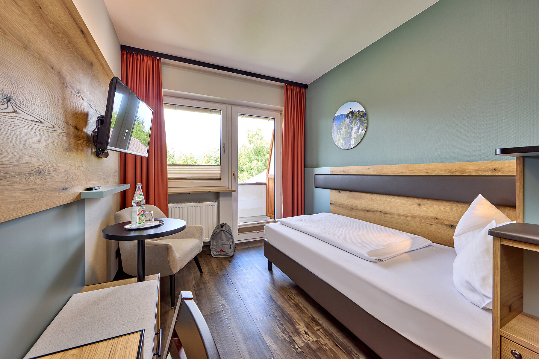 Zimmeransicht in Richtung Fenster. Links die Sitzgelegenheiten, rechts das gemütliche Bett