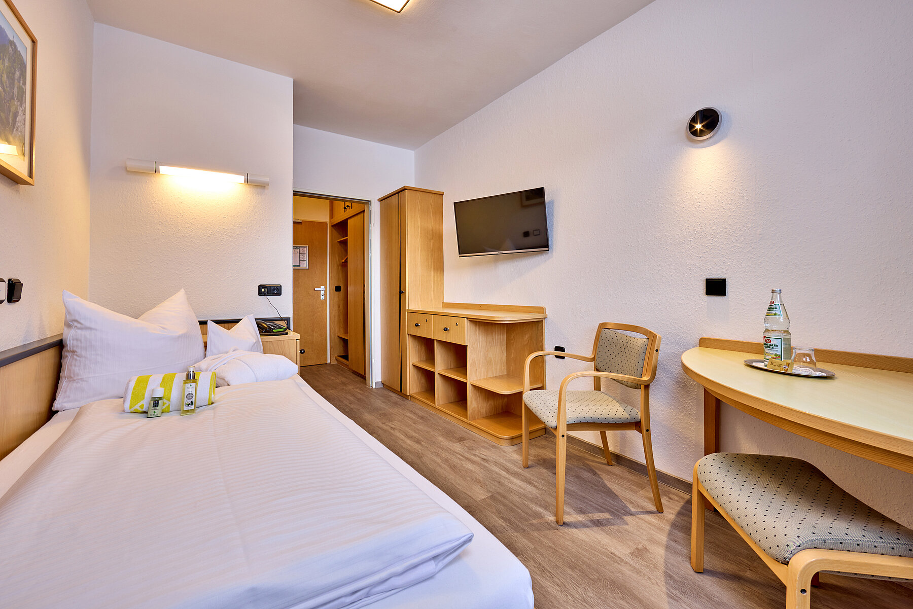 Das Einzelzimmer ist klassisch mit Bett, Sitzecke, TV-Wand und großer Ablagekommode eingerichtet.