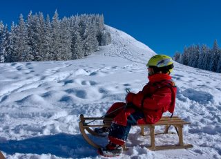 Ein Mädchen auf einem Holzschlitten im Schnee