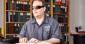 Ein blinder Gast liest ein Brailleschrift-Buch in der Bibliothek