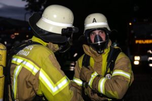 Zwei Feuerwehrleute tragen eine Atemschutzausrüstung