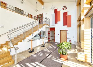 Der modern gestaltete Eingangsbereich des Seminargebäudes mit hohen Wänden und einer Treppe