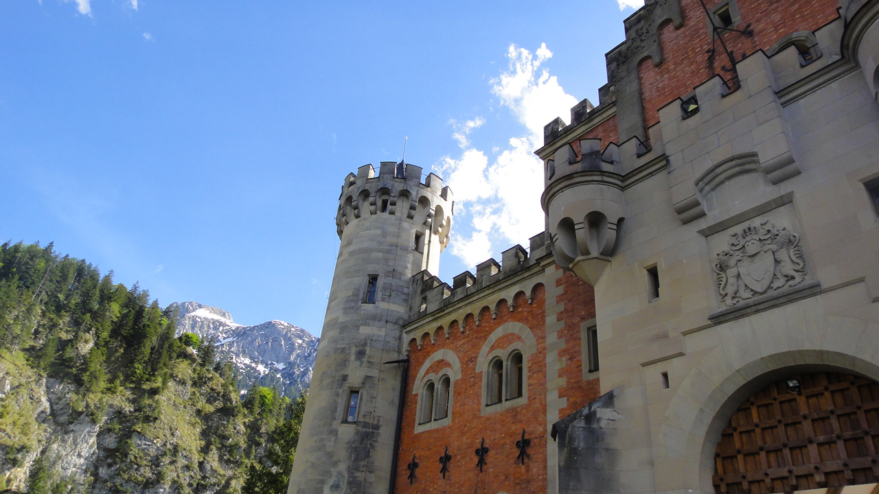 Schlossturm und Schlosstor vor einer Bergkulisse