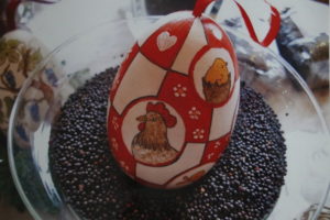 Ein rot weißes bemaltes Ei mit einer Henne und einem Kücken