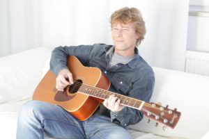Der Musiker sitzt auf einem Sofa und spielt Gitarre