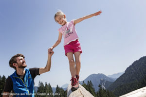 Ein kleines Mädchen balanciert über einen Holzbalken