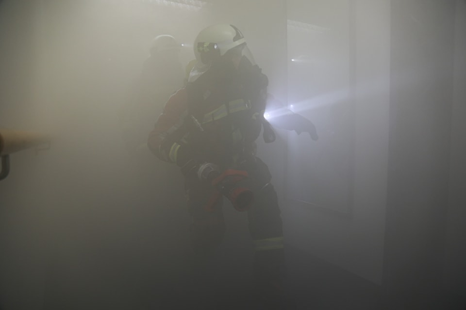 Der Raum ist mit Rauch gefüllt, durch den ein Feuerwehrmann mit Atemschutz eilt.