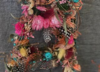 Die Silhouette eines Hasen geschmückt mit bunten Blüten, Federn und anderen Naturmaterialien.