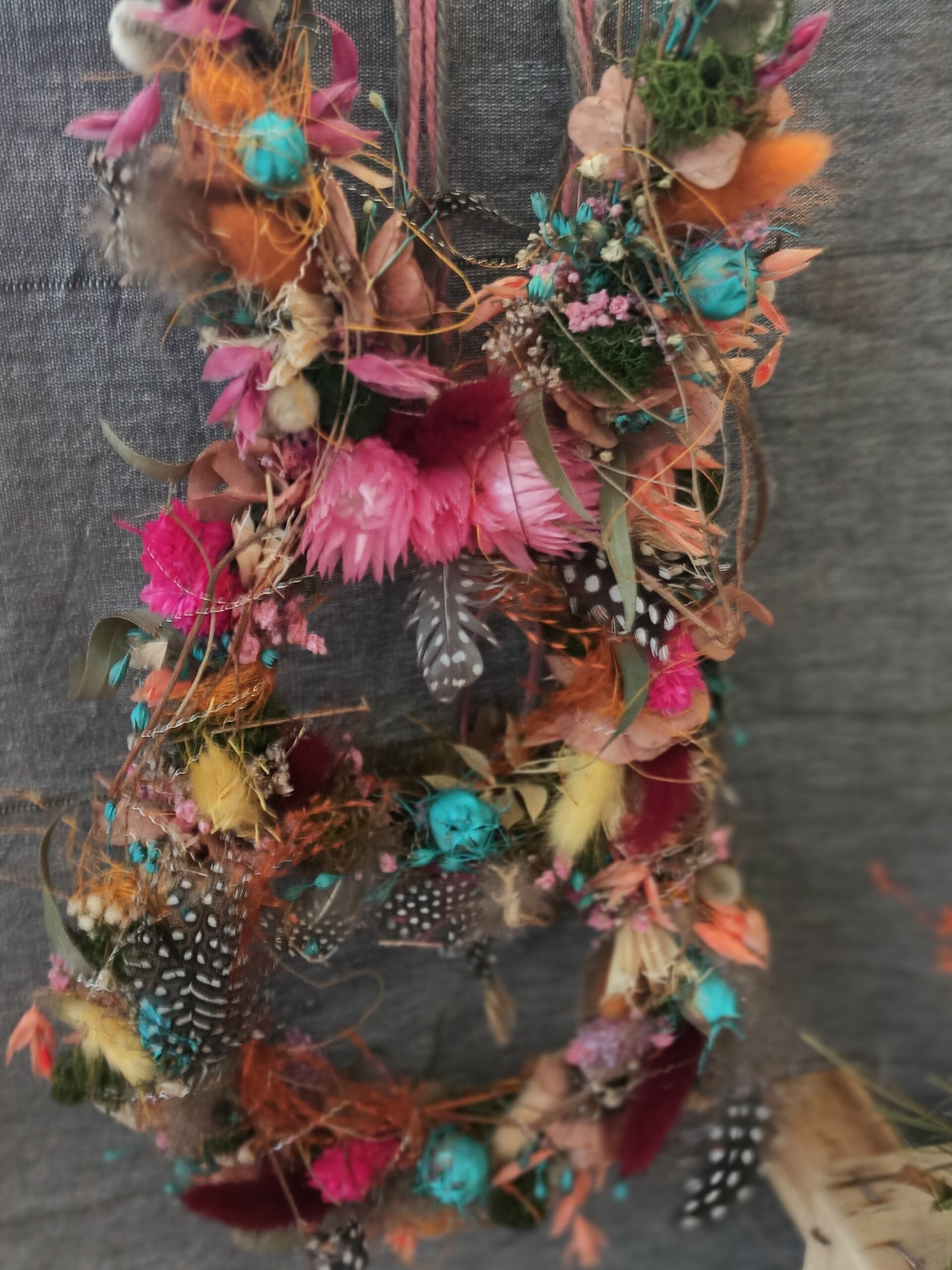 Die Silhouette eines Hasen geschmückt mit bunten Blüten, Federn und anderen Naturmaterialien.