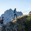 Zwei Wanderinnen gehen am Drahtseil für einen Berggrat