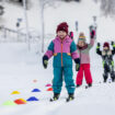 Fröhliche Kinder sammeln erste Erfahrungen auf Skiern