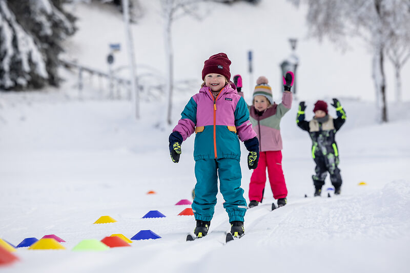 Fröhliche Kinder sammeln erste Erfahrungen auf Skiern